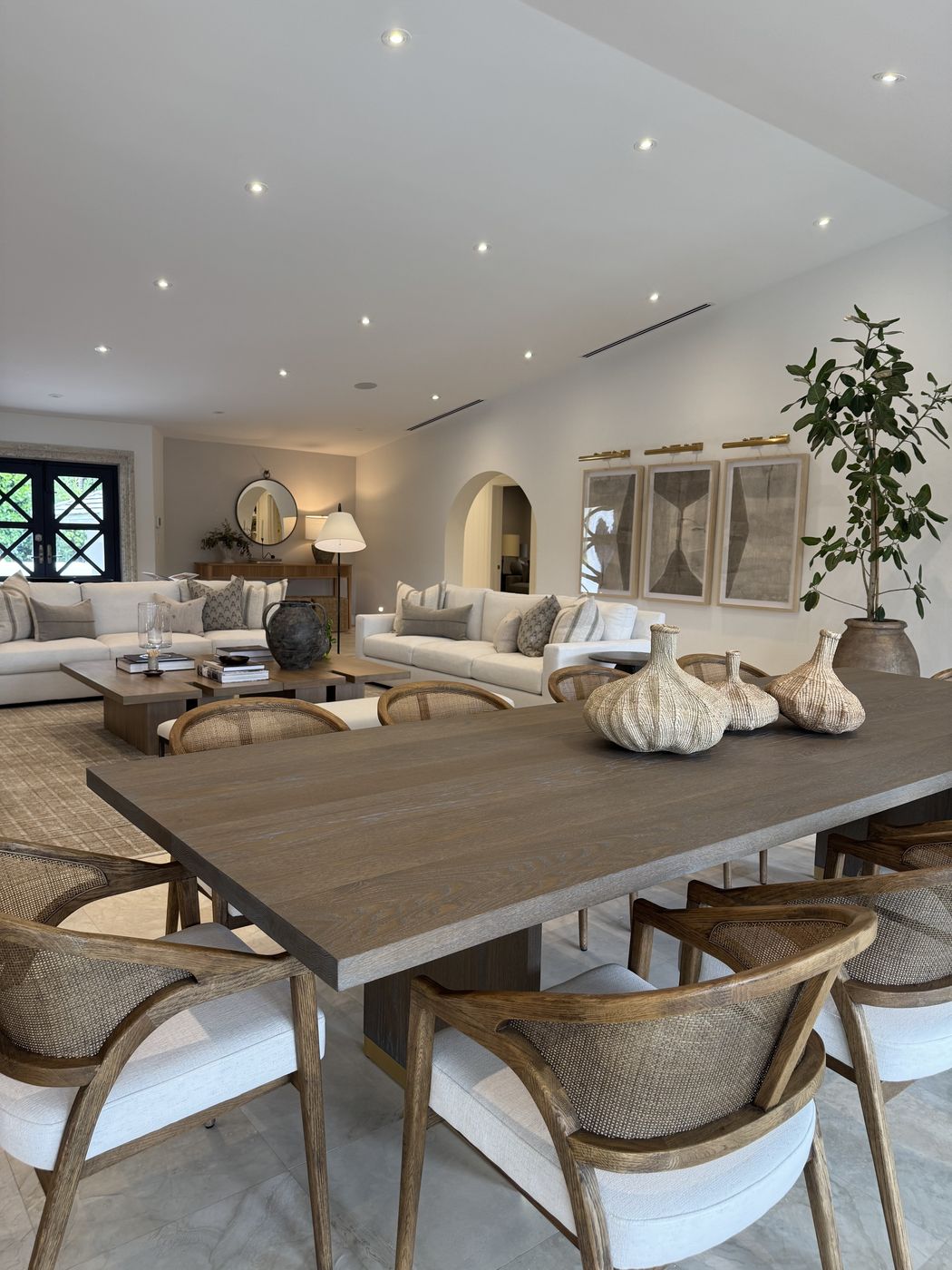 Open dining and living space with gray-washed table and cream sofas