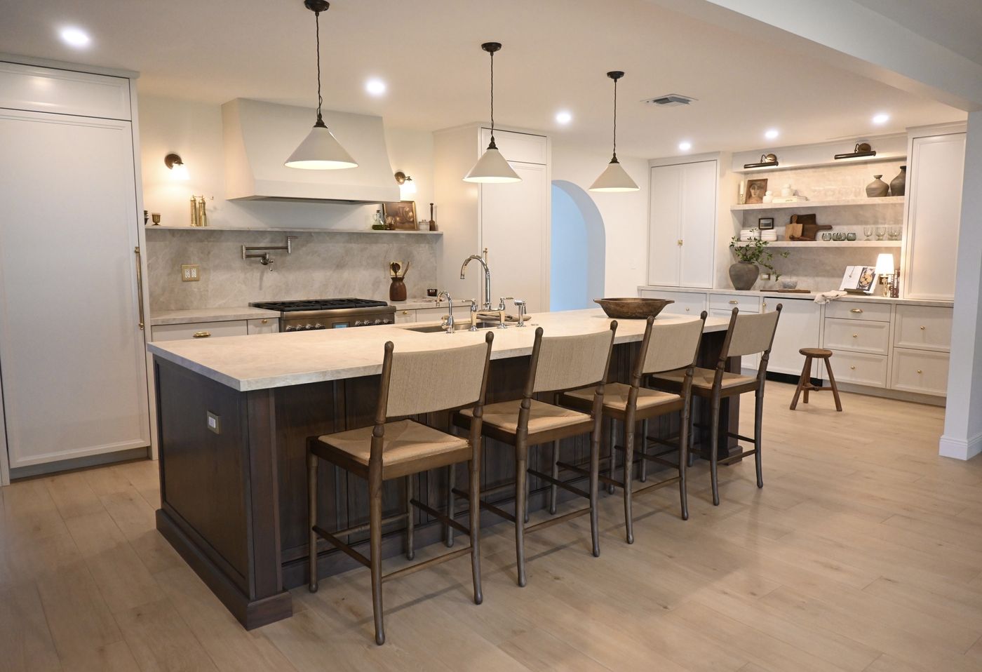 Kitchen with dark-stained island, woven bar stools, and cone pendants